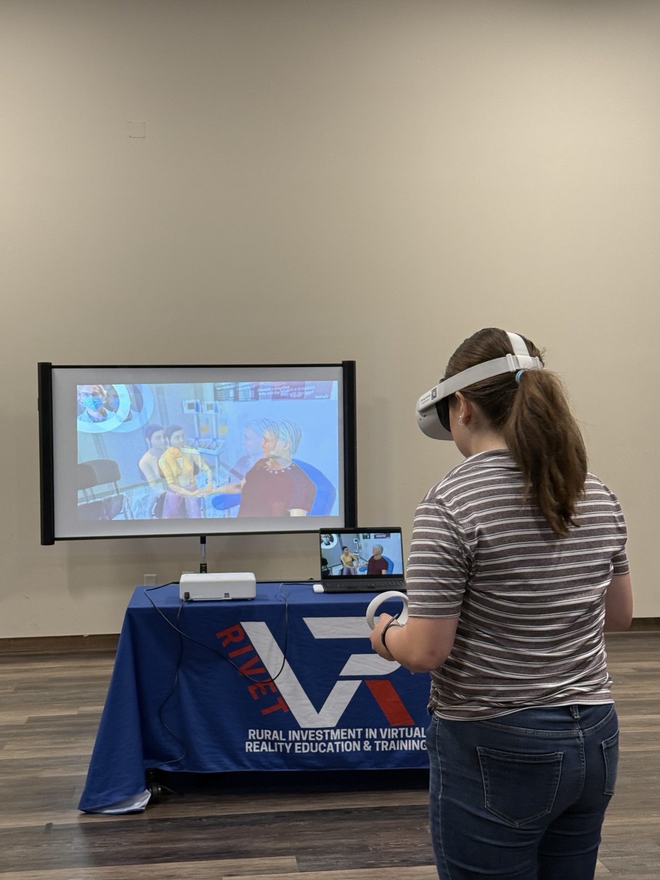 A RIVET participant in a VR headset with the session shown on a screen